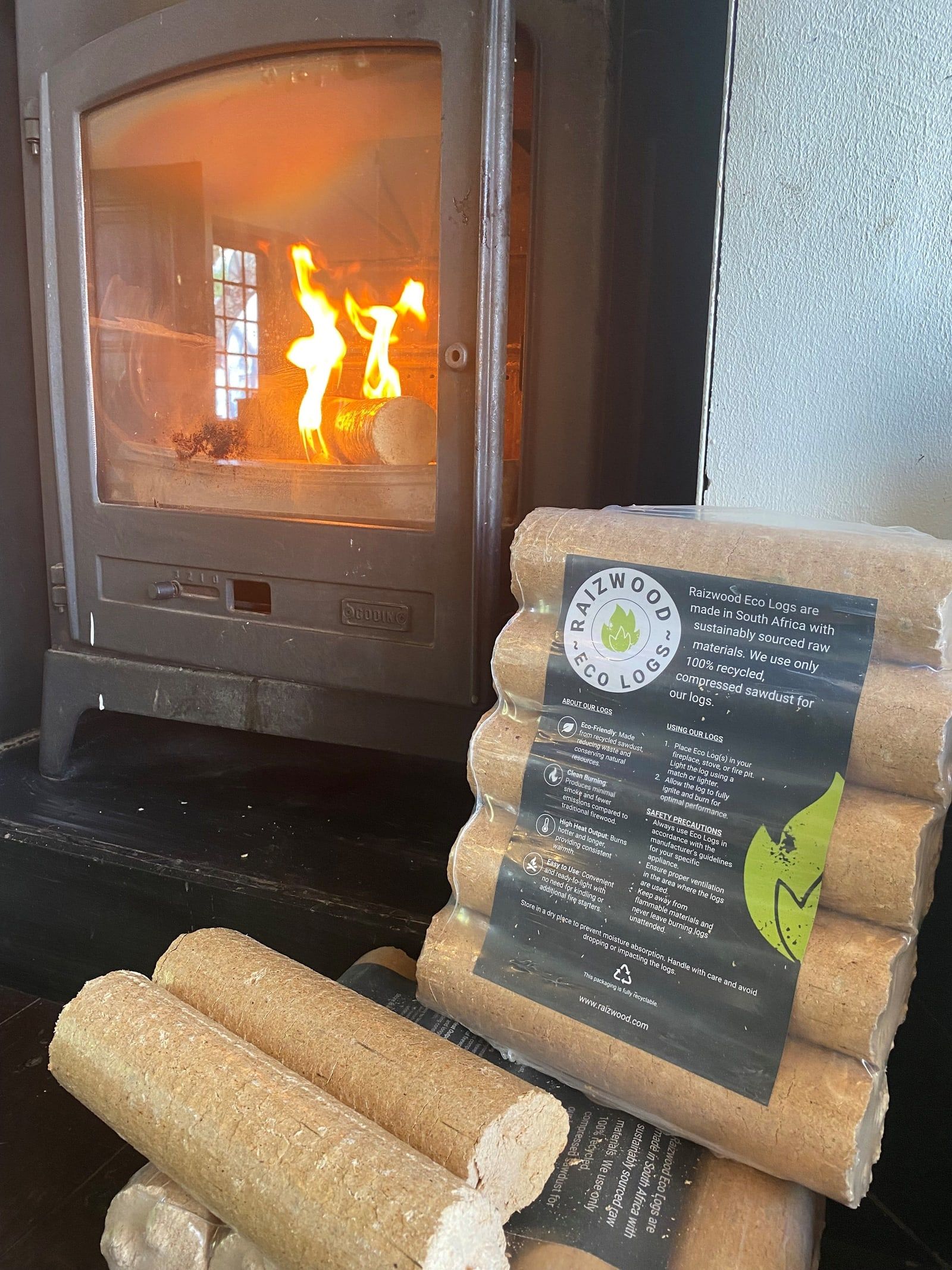 Raizwood Eco Logs packs and loose logs next to a wood-burning stove